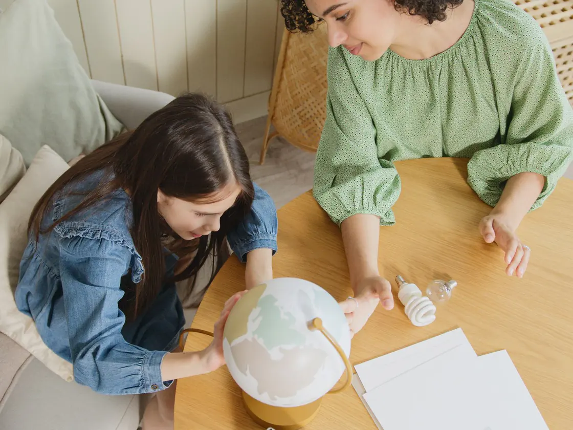 A parent and child studying a globe together at home