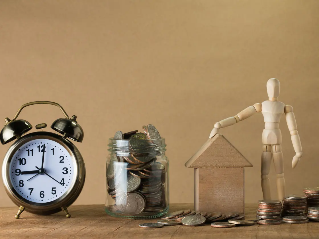 A clock, coin jar and model house representing long-term saving